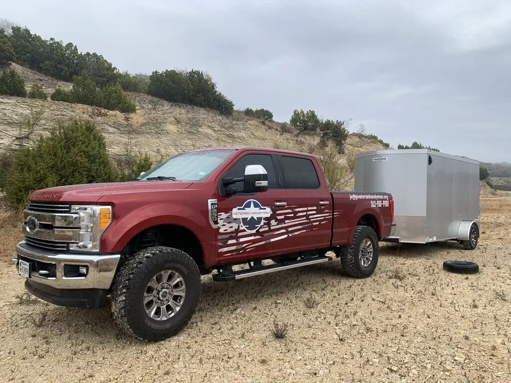 The Veteran Handyman truck and enclosed work trailer parked on a Texas Hill Country job site