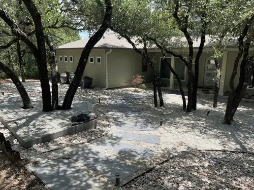 Shaded courtyard with a bluestone stepping-stone path, gravel beds and a composite deck under live oaks