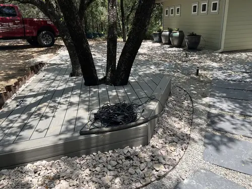 Composite deck built around a live oak with steel edging and a crushed-stone border