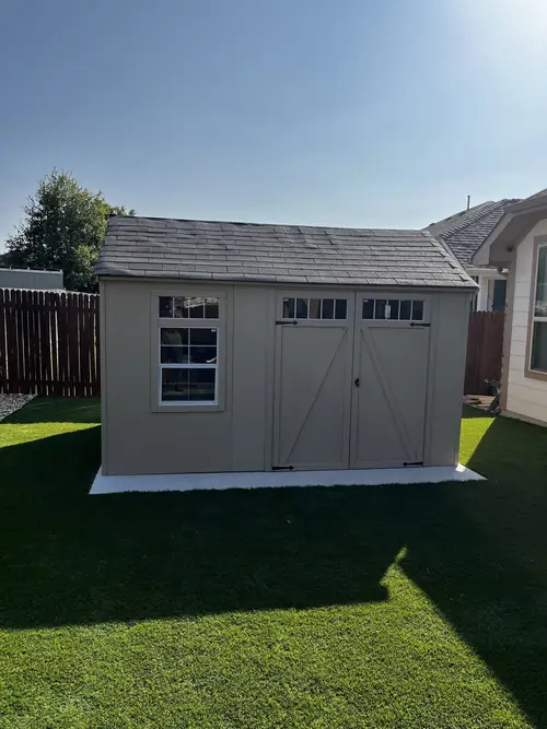 Storage shed set on a level pad over artificial turf in a fenced back yard