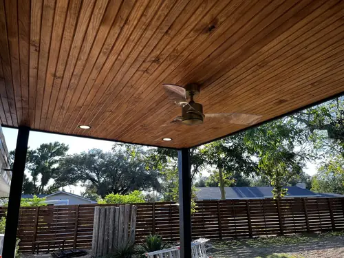 Underside of a cedar patio-cover ceiling fitted with a fan and recessed lights