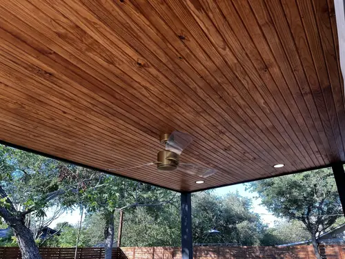 Stained wood patio ceiling with recessed lighting and a ceiling fan