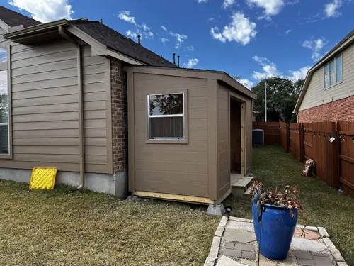 Storage shed built on a level base beside a home's side yard