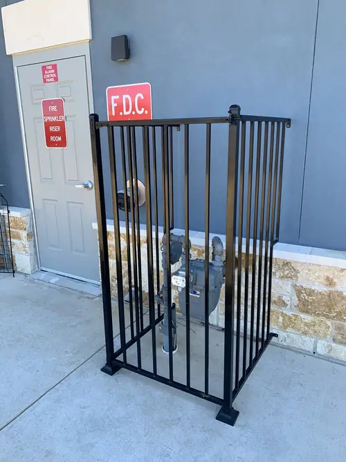 Powder-coated steel guard enclosing a fire-department connection and gas meter
