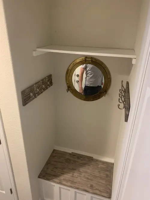 Finished mudroom nook with a built-in bench, floating shelf and coat hooks